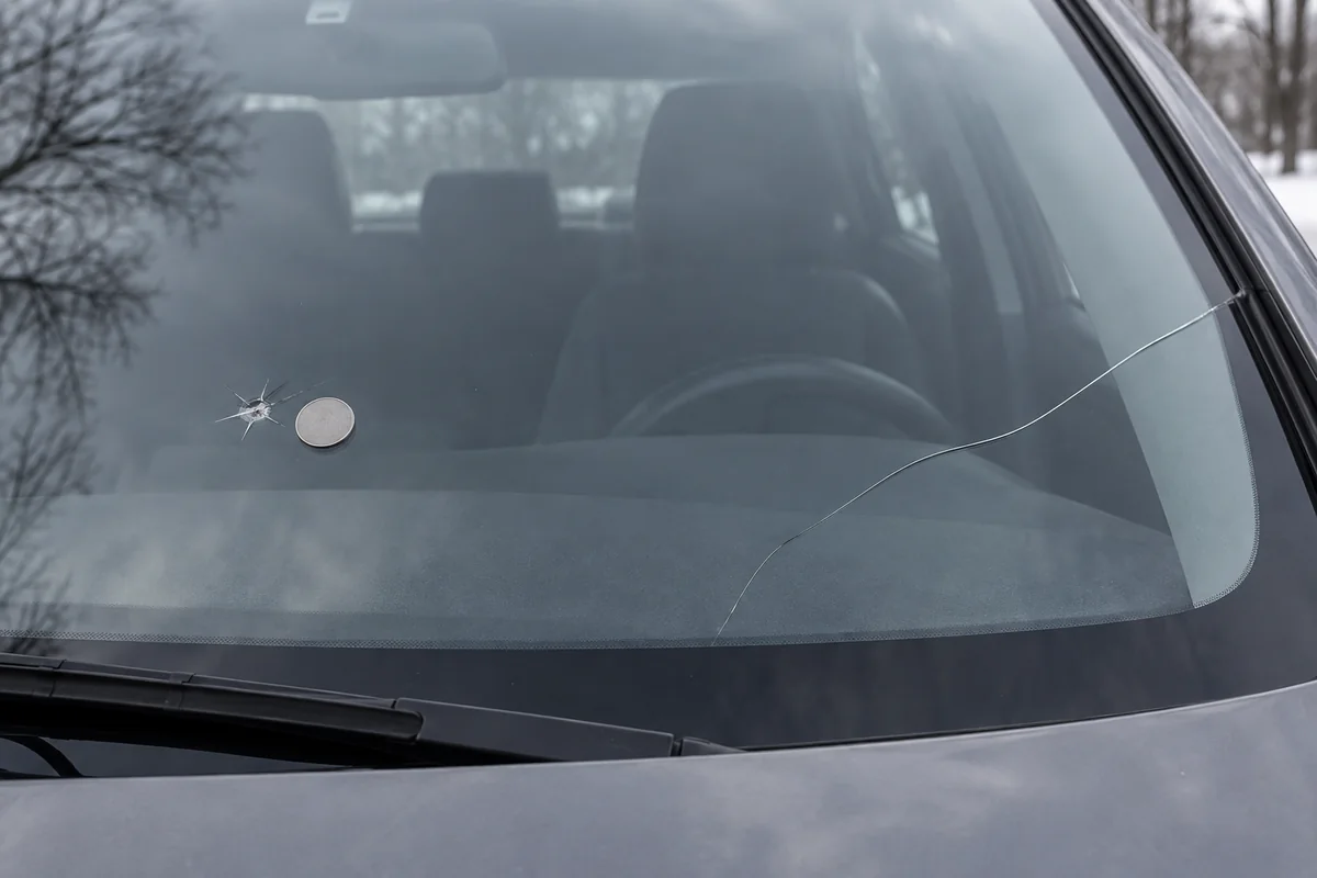 Windshield with a small chip beside a replacement glass sample