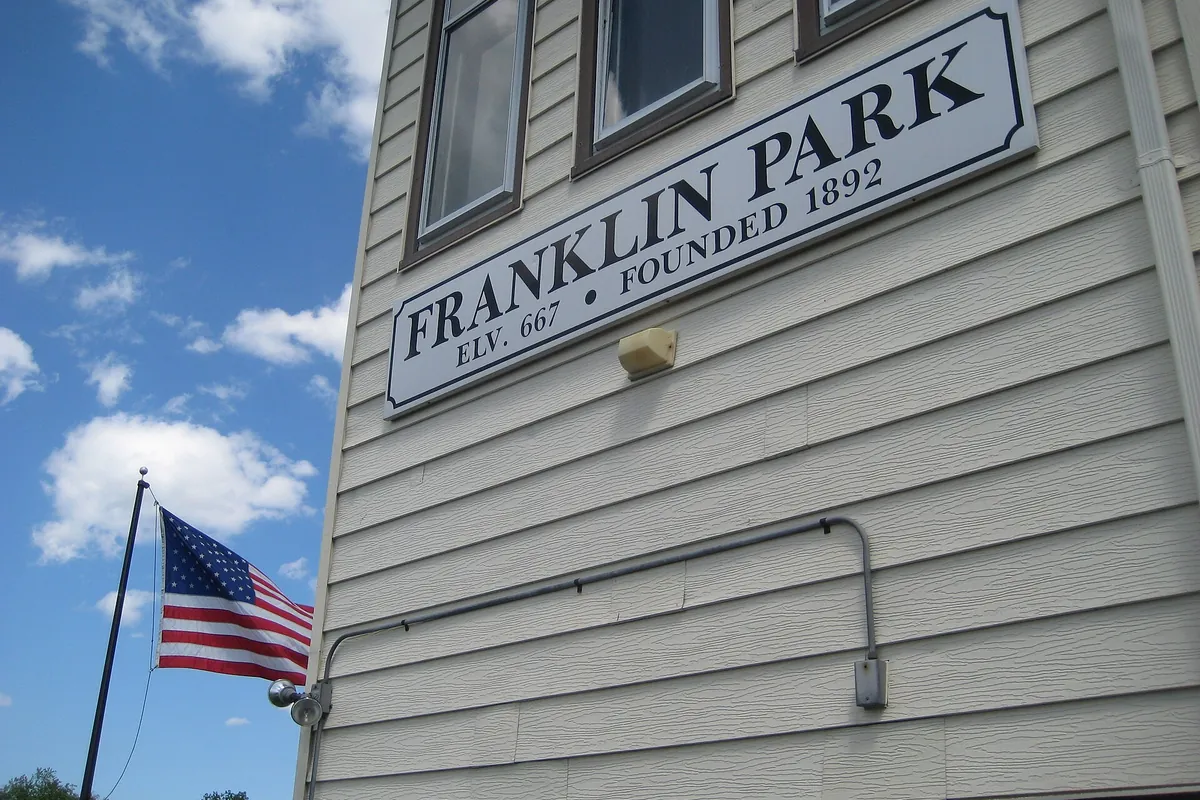 Franklin Park, Founded 1892 sign on a white clapboard building beside a U.S. flag